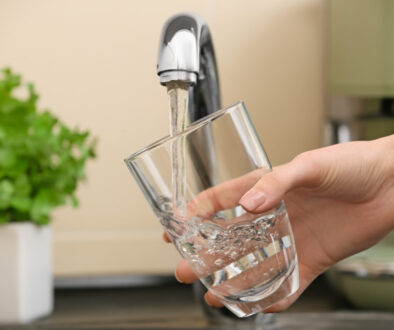 Woman filling glass with fresh water from kitchen faucet Woman filling glass with fresh water from kitchen faucet