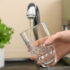 Woman filling glass with fresh water from kitchen faucet
